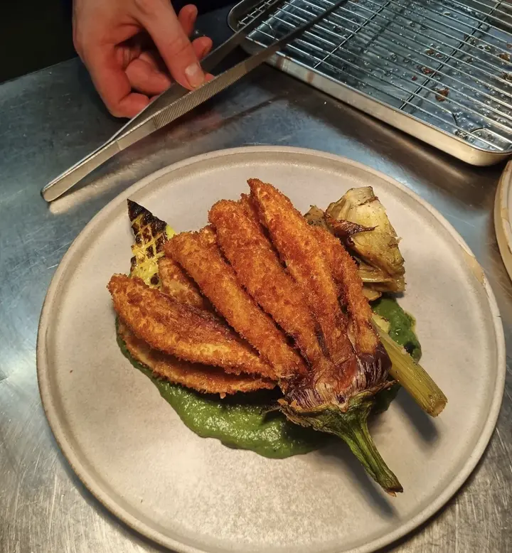 Une assiette d’artichaut doré et croustillant sur une sauce verte